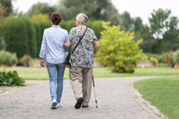 Happy senior woman and caregiver walking outdoors